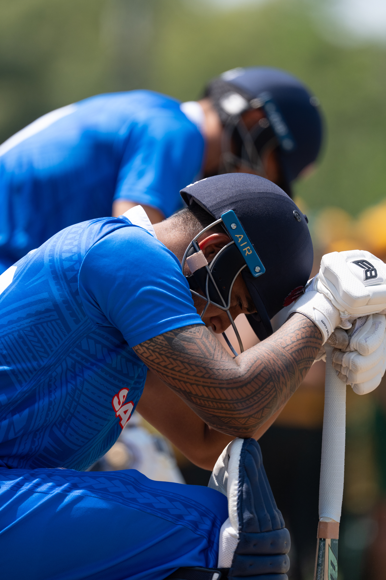 Samoa batsman resting on his bat with Samoan tatau visible on his arm
